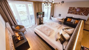 Una habitación de hotel moderna con una cama grande, un sofá, un televisor y una chimenea.