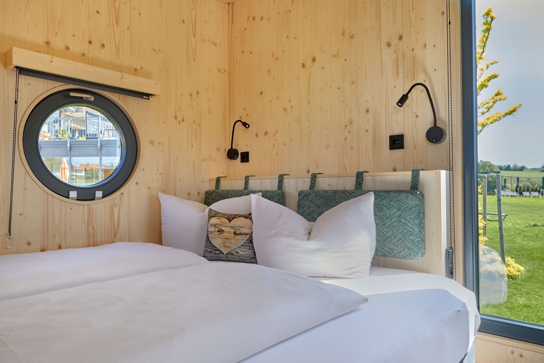 Un dormitorio con una cama grande, un ventanal redondo y vistas al exterior.