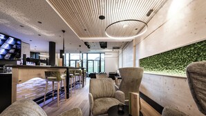 Un área de descanso moderna con asientos cómodos, una barra y un ventanal con una pared verde.