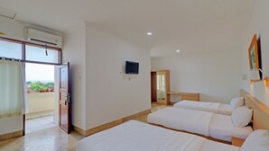 A hotel room with two beds, a TV, and a balcony with curtains. - Hotel O Simalem Guest House (Kuta)