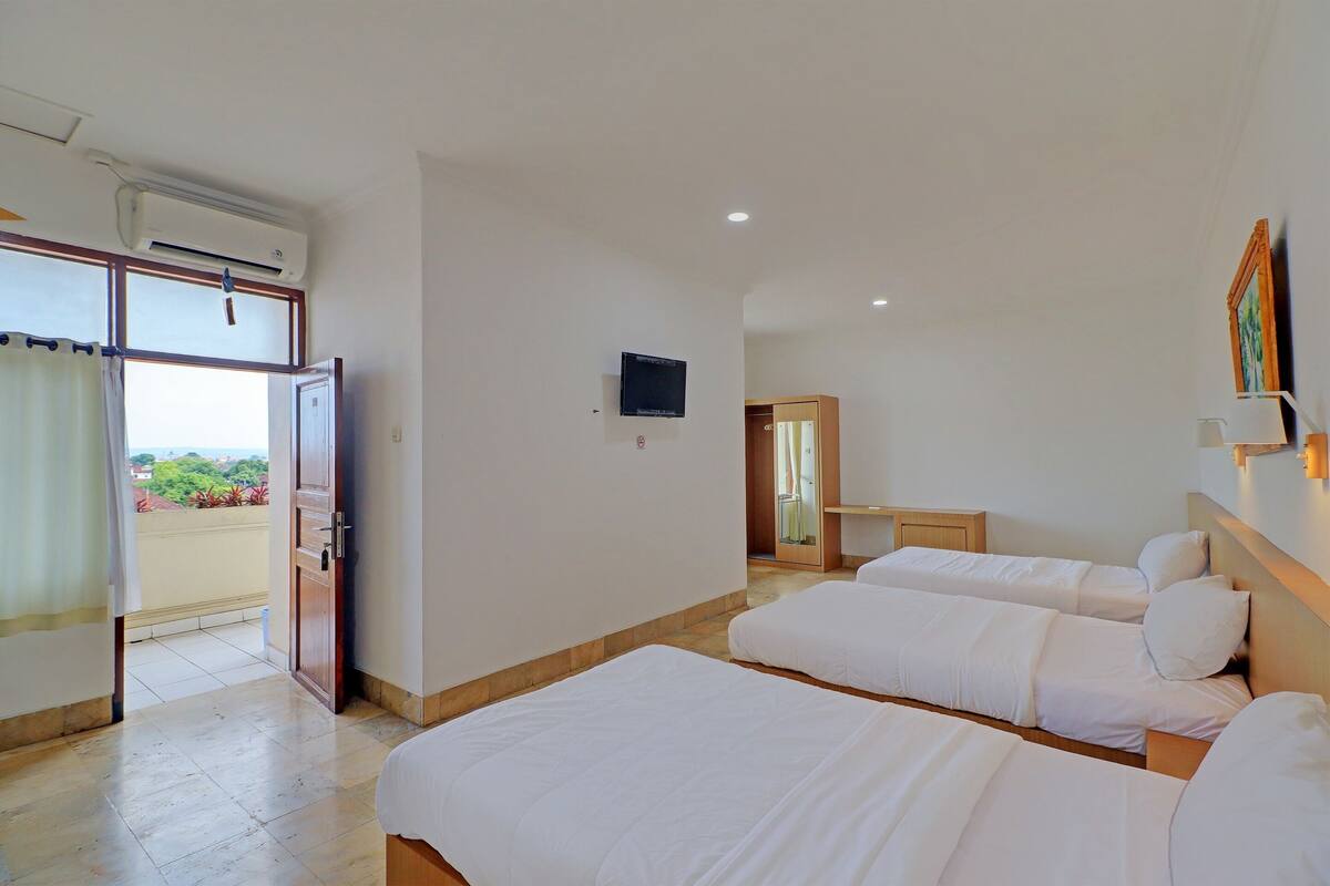 A hotel room with two beds, a TV, and a balcony with curtains.