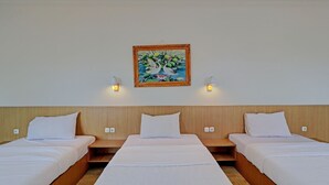 A hotel room with three single beds, wooden headboards, white bedding, and a painting on the wall. - Hotel O Simalem Guest House (Kuta)
