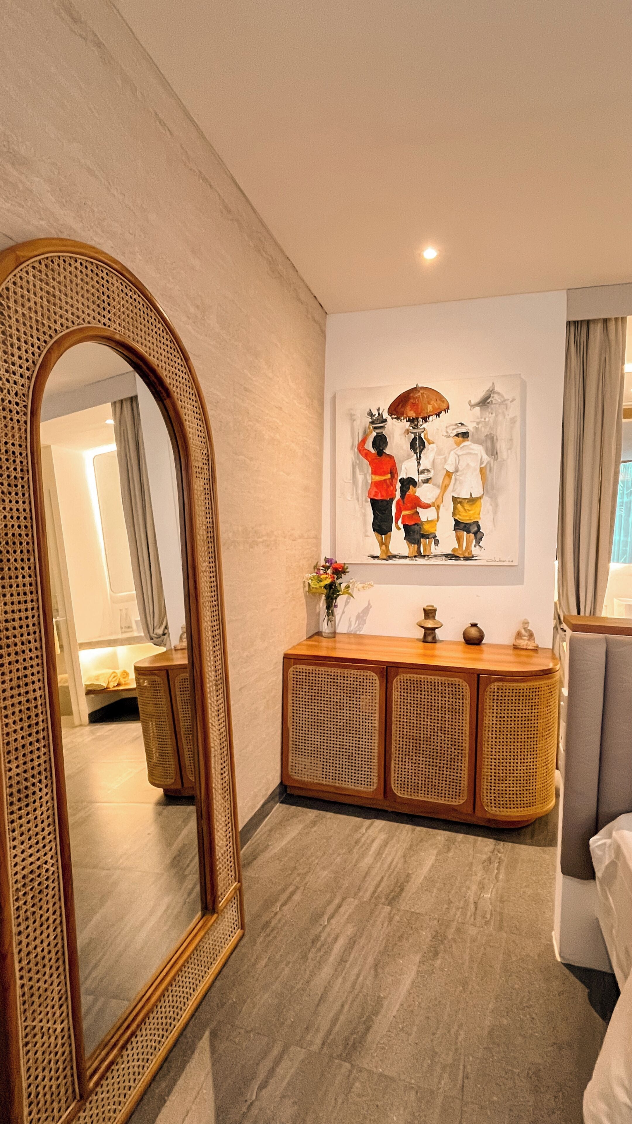 Een moderne hotelkamer met een grote spiegel, een houten console tafel, een schilderij en een bed.