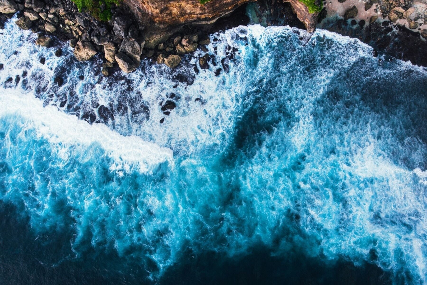 A turbulent ocean wave crashing against a rocky shore.