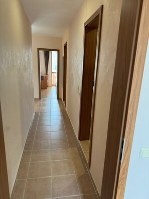 Corridors lead to rooms with beige walls and wooden doors.