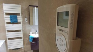 A bathroom with a towel rack, a mirror, and a wall-mounted control panel. - Maison Bonhage (Chaumont)