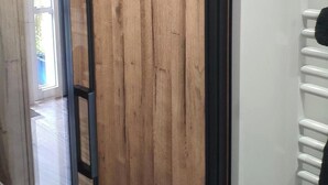 A room with a wooden panel wall, a glass door leading outside, and a white radiator. - Maison Bonhage (Chaumont)
