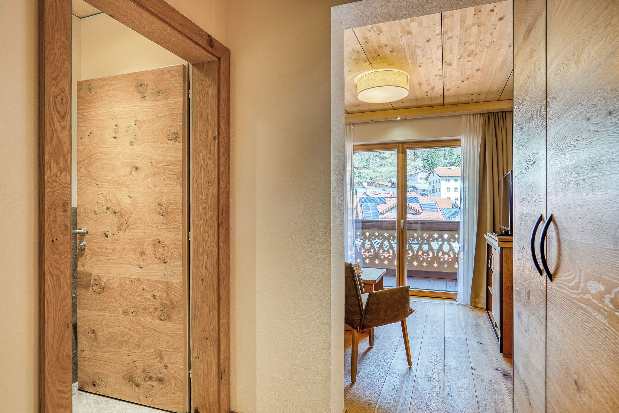 Interior de madera con un panel corredizo de vidrio que da a un espacio exterior con vistas a edificios y un balcón.