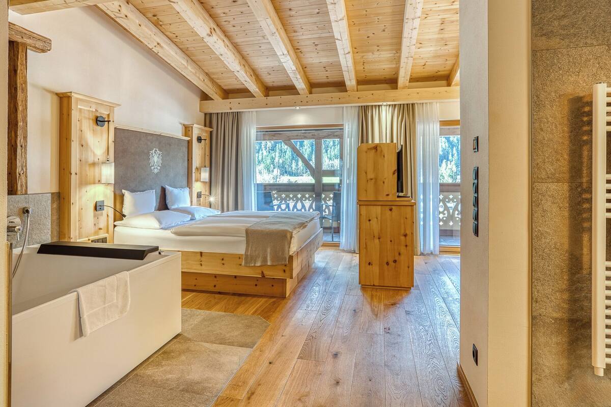 A wooden cabin interior with a bed, a wooden cabinet, and a view of the outdoors.