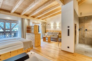 Ein Holzinnenraum mit Bett, Sofa und Dusche.