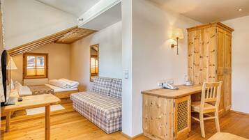A cozy room with a bed, a sofa, a desk, and a wooden cabinet.