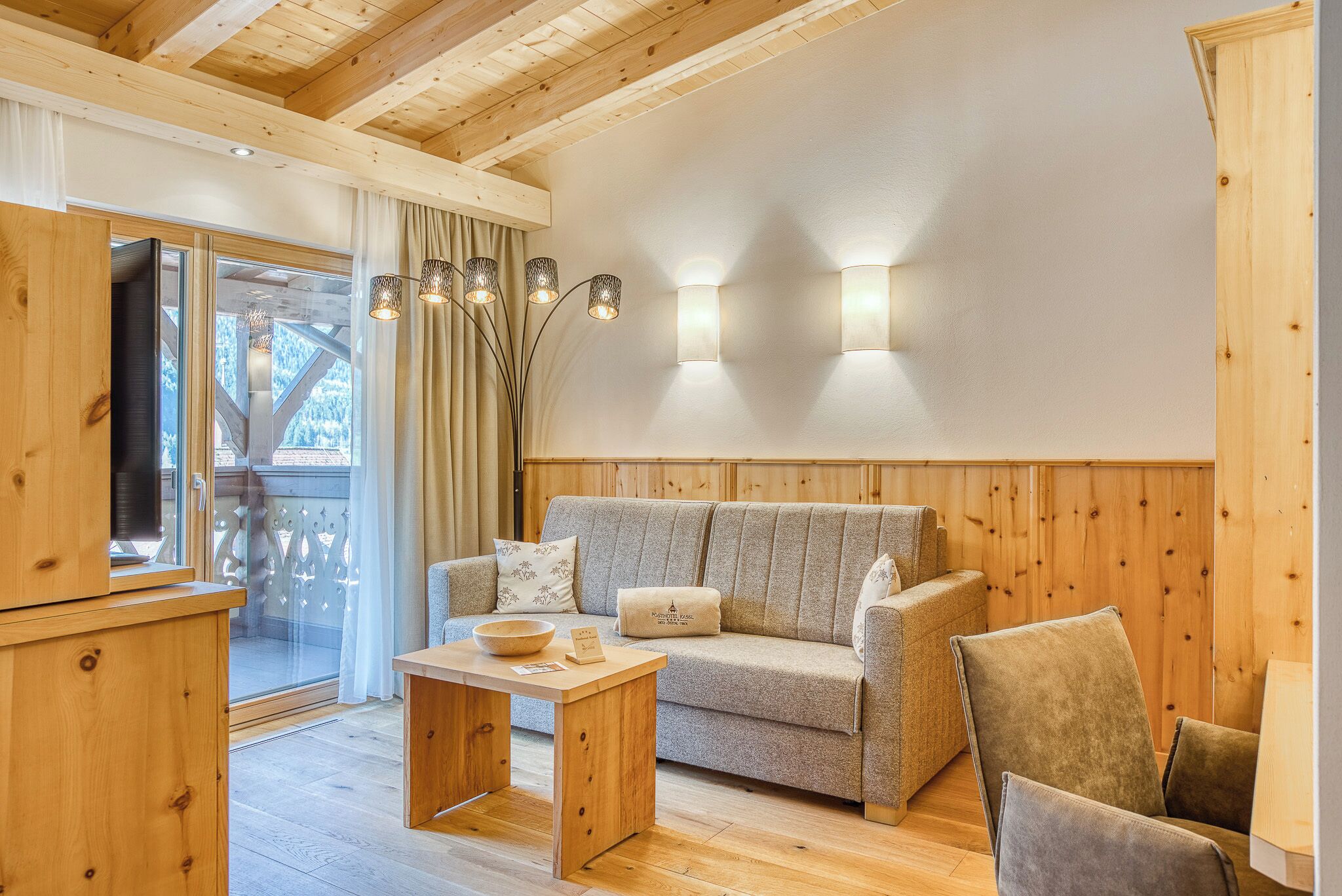 A wooden interior with a sofa, a table, and a TV.