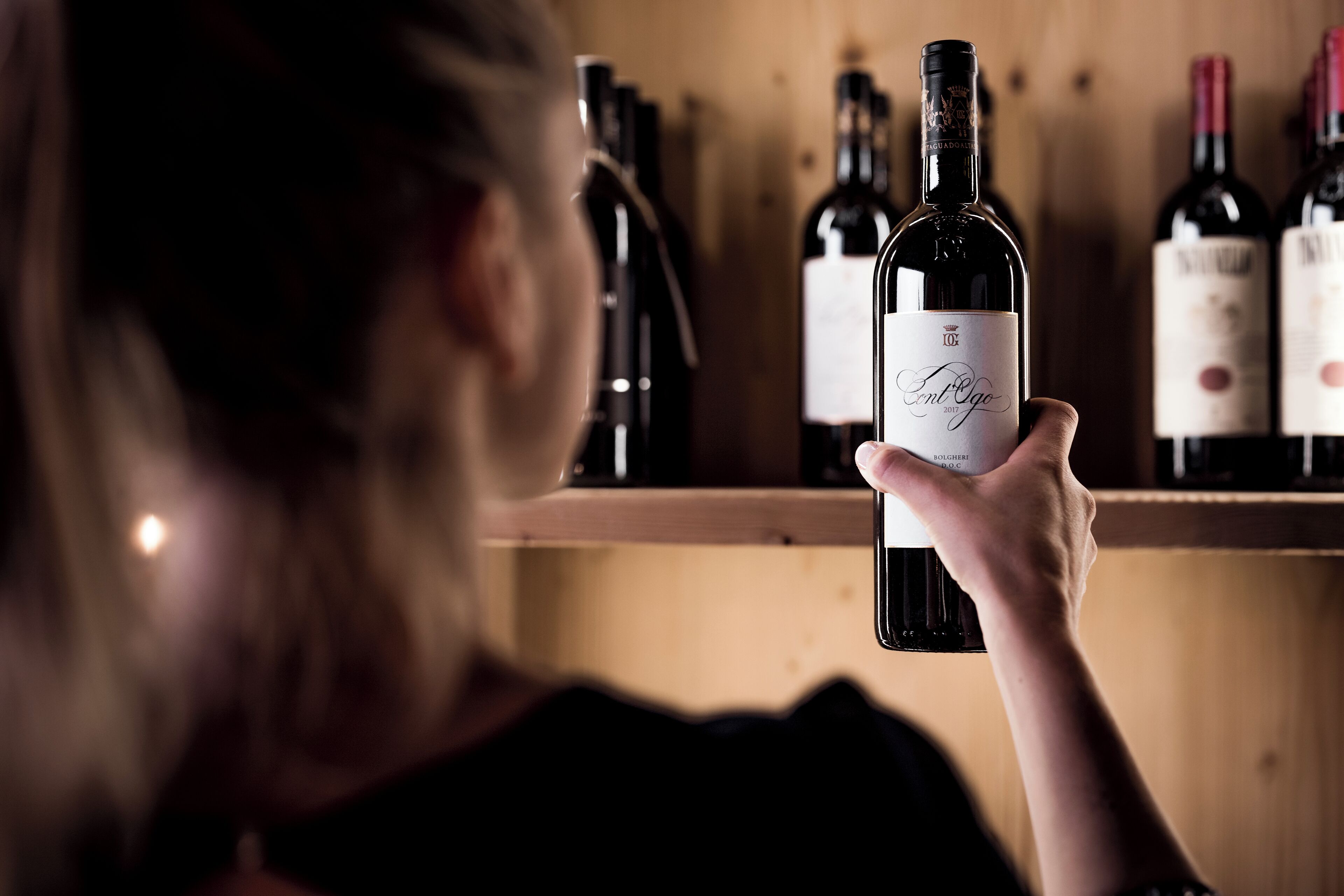 Una persona sostiene una botella de vino con una etiqueta que dice "Antique 2017".