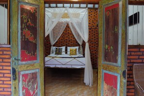 A room with a bed, a mosquito net, and a brick wall. - Hotel O Holy HomestayNearWisata Kopi Desa Tamansari (Banyuwangi)