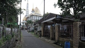 Una calle estrecha con un letrero que dice "HOLLY HOME STAY" y un edificio con cúpula al fondo.
