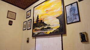 Pared decorada con varias obras de arte enmarcadas, incluyendo un cuadro grande de un paisaje al atardecer y varias fotografías más pequeñas.