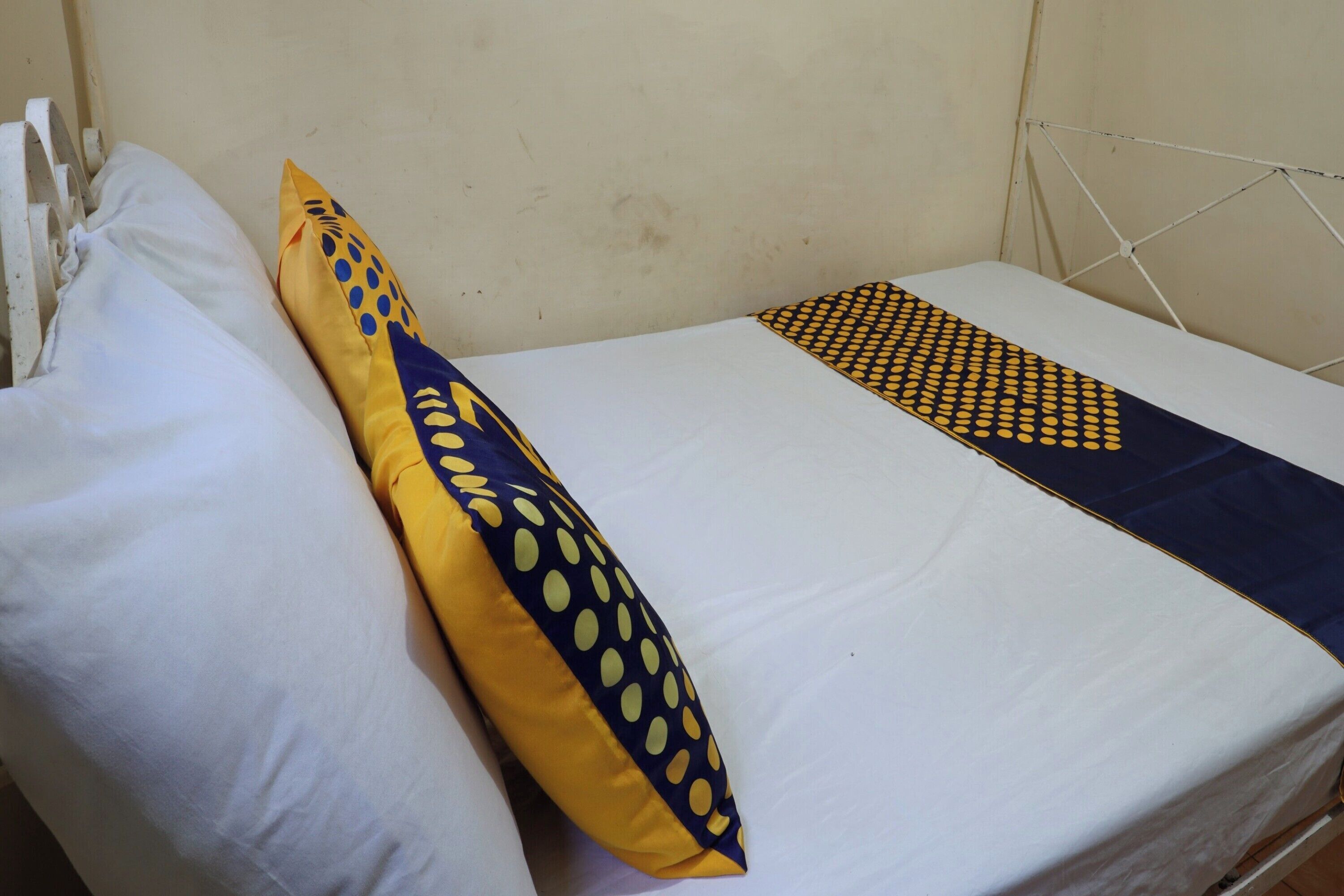 A single bed with a white mattress and a blue and yellow pillow.