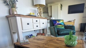 A living room with a wooden coffee table, a sofa, a TV, and a lamp. - Gleann Ciuin (Newry)