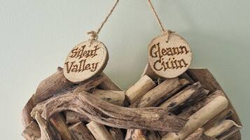 A rustic wooden nest with two wooden tags hanging from a branch, and a small owl figurine above.