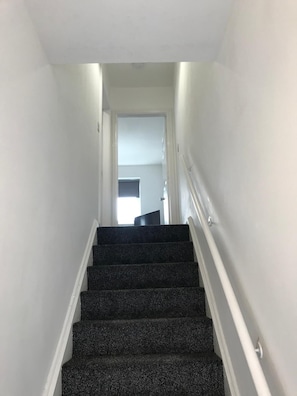 A staircase with a handrail, leading to an interior space with a door at the top.