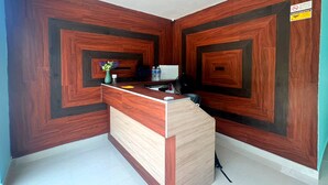 A reception area with a wooden reception desk, a whiteboard, and a security camera on the ceiling.