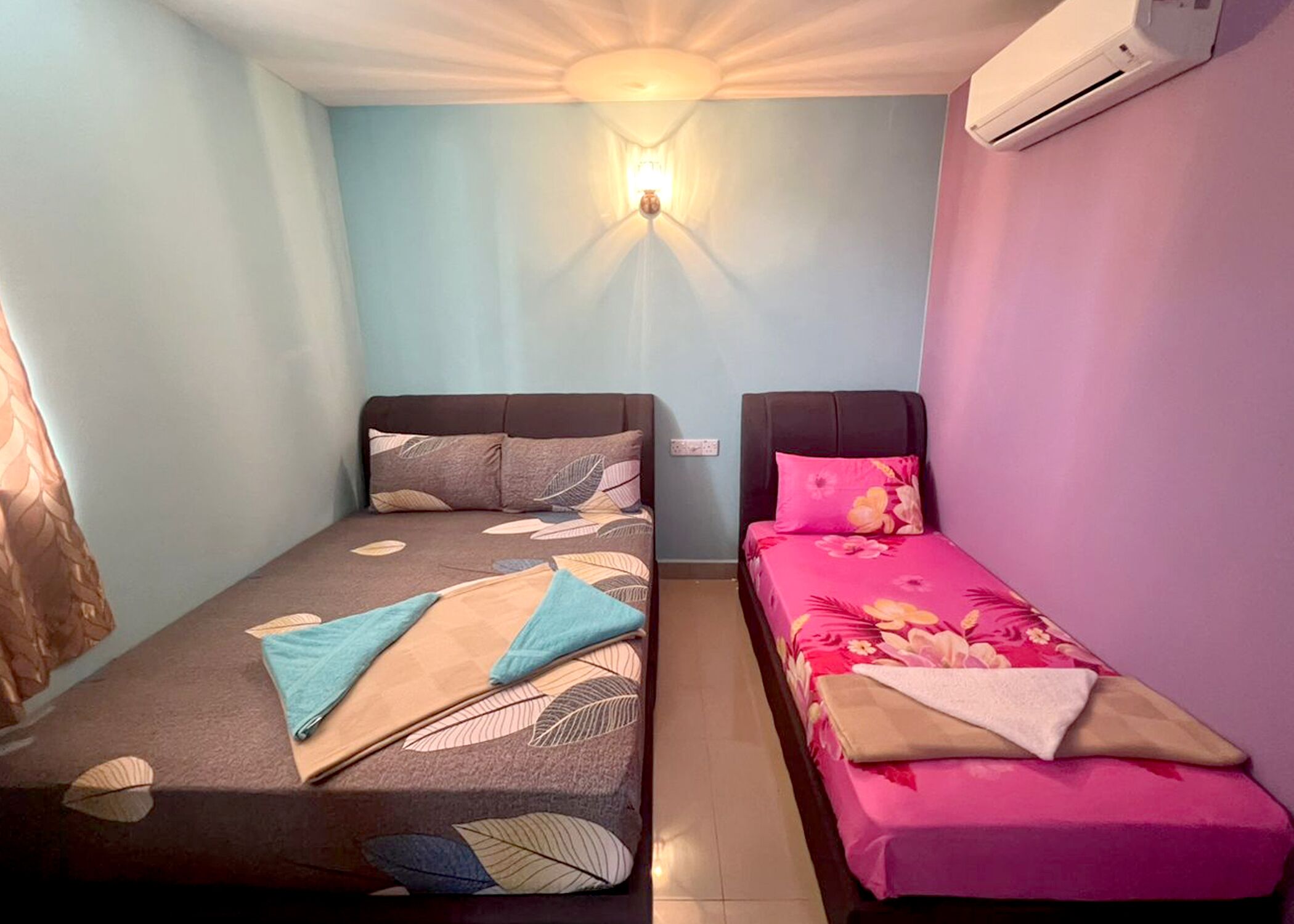 Una habitación pequeña con dos camas individuales, aire acondicionado instalado en la pared y una lámpara en el techo.