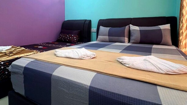 A hotel room with a large bed, two pillows, a wall-mounted air conditioner, and a ceiling light.