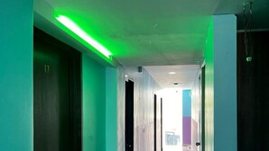 A corridor with teal walls, a green-lit ceiling, and a door marked with the number 17.