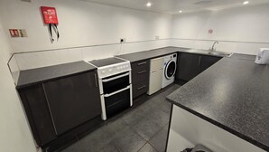 Uma cozinha compacta com fogão, forno, máquina de lavar e pia.