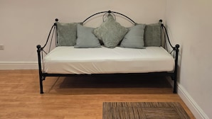 Cama com estrutura metálica, roupa de cama branca e vários travesseiros.