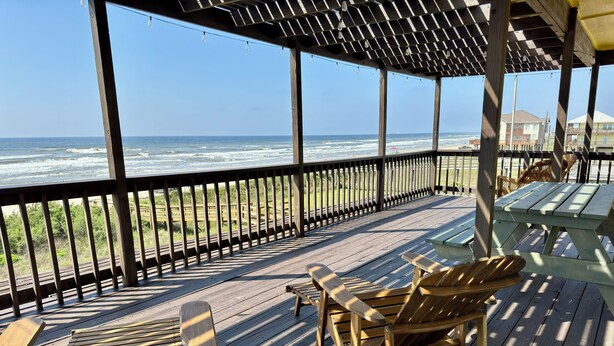 A wooden deck with seating, overlooking the ocean.