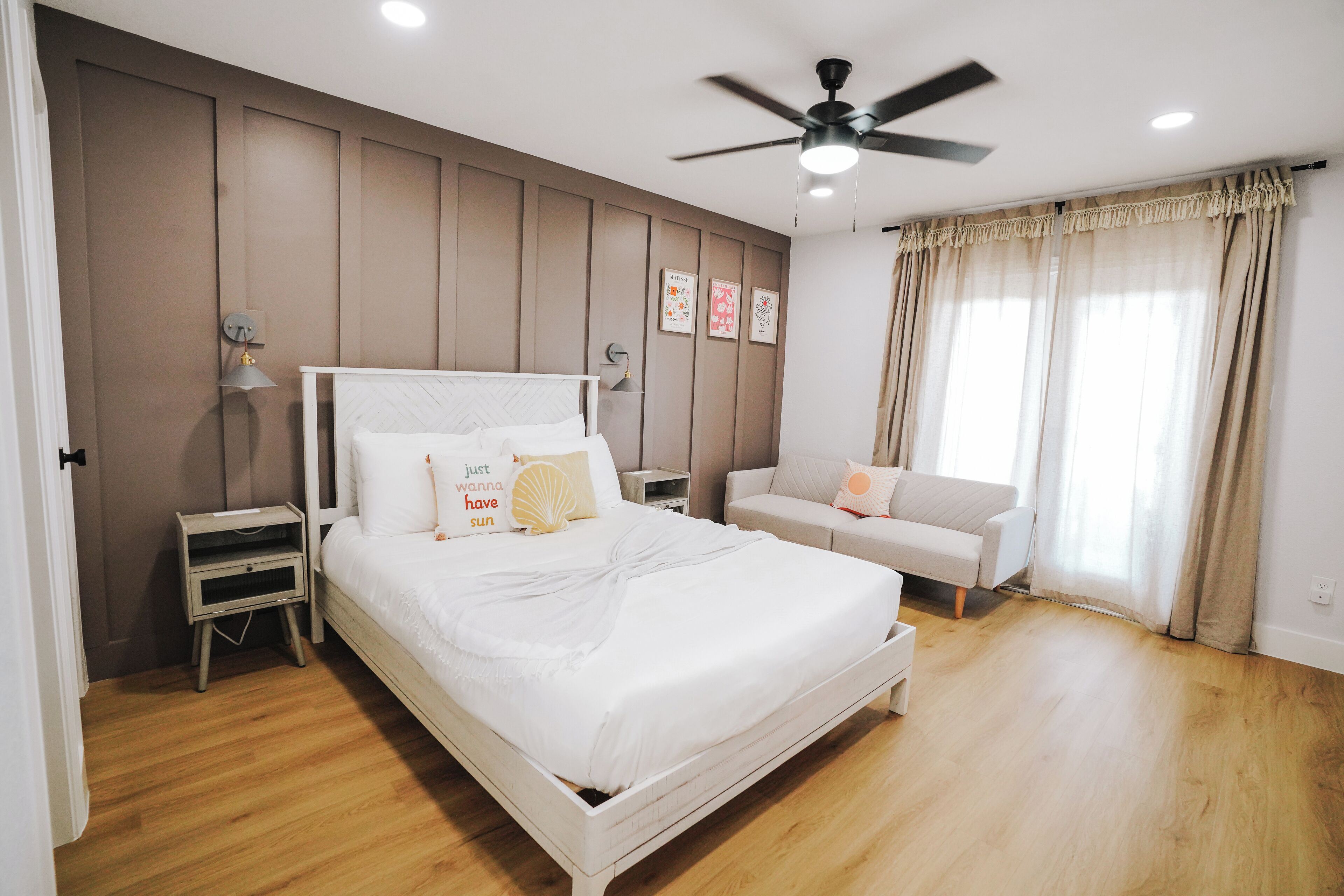A bedroom with a bed, bedside tables, a ceiling fan, and a window with curtains.