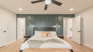 A bedroom with a bed, bedside tables, a ceiling fan, and a bench at the foot of the bed.