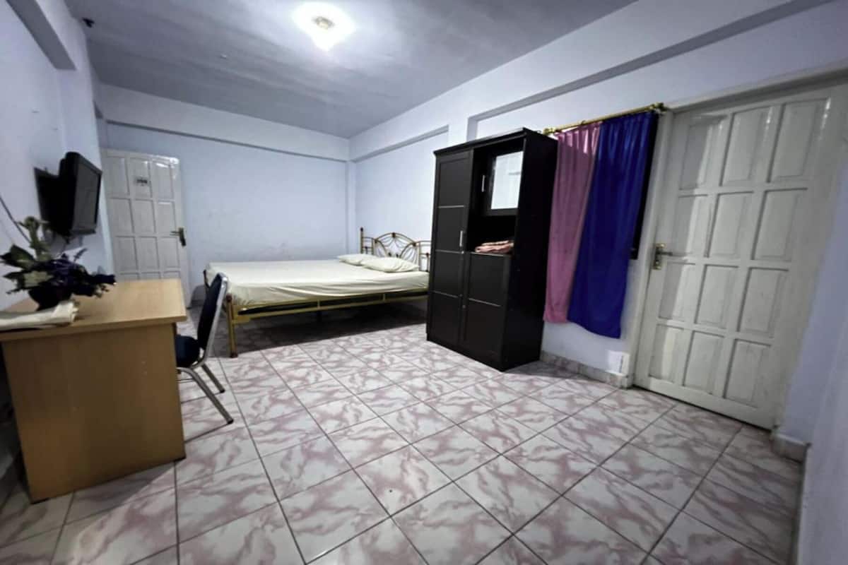 A bedroom with a bed, a wardrobe, a desk, and a television.