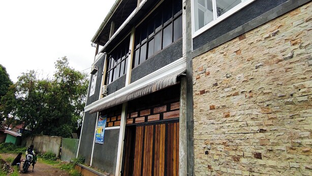 Un edificio de dos plantas con fachada de piedra y una gran puerta de madera.