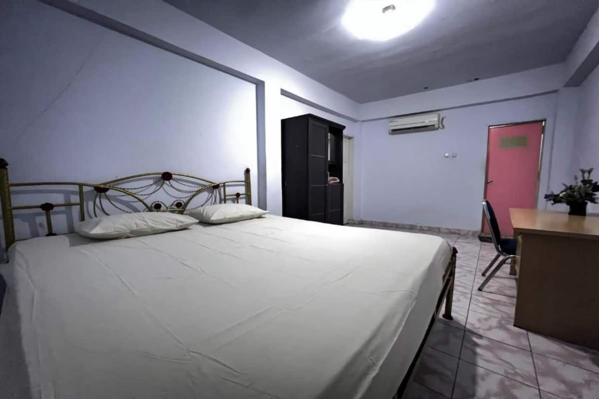 A bedroom with a bed, a desk, and a wardrobe.