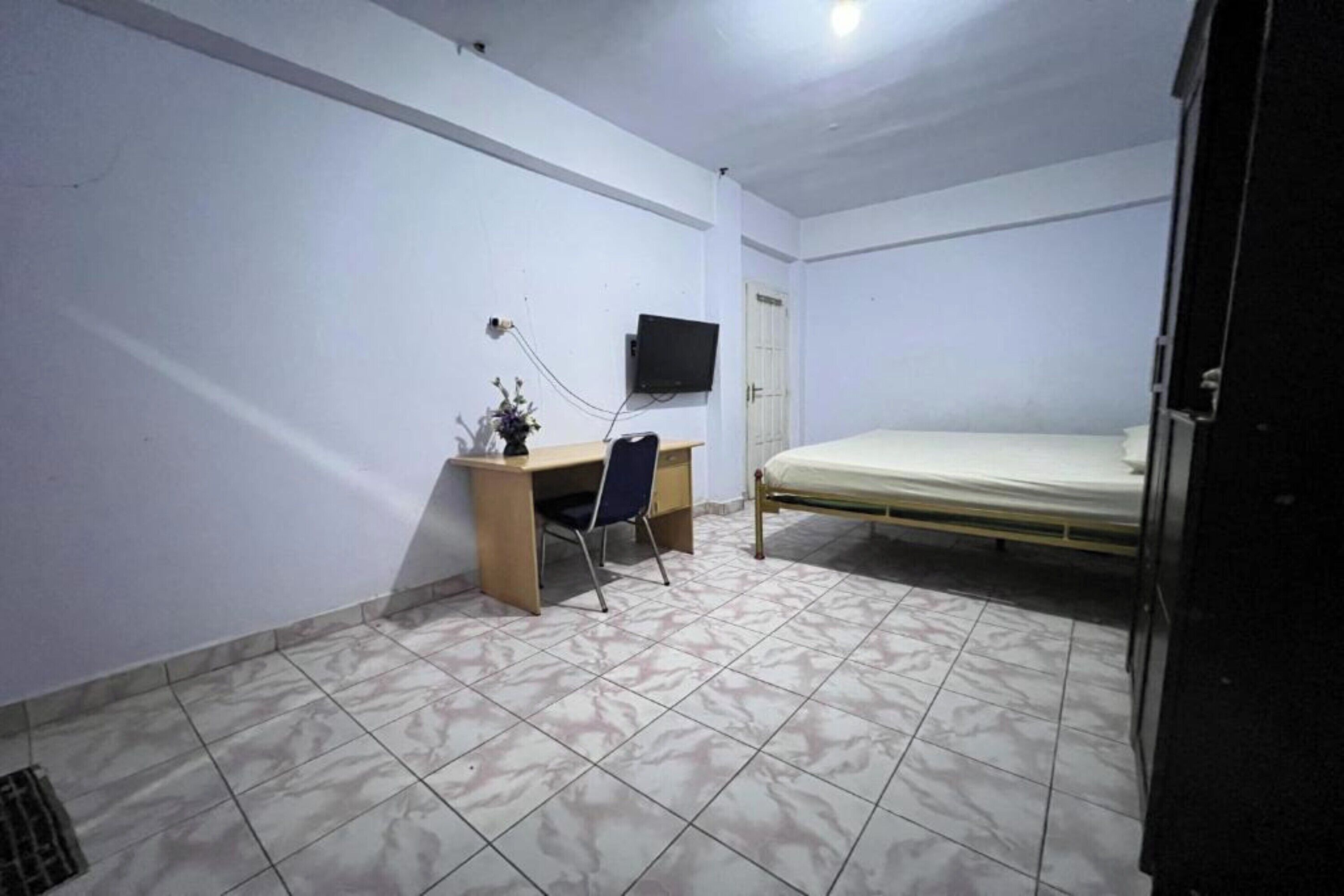 A bedroom with a bed, a desk, a chair, and a television.