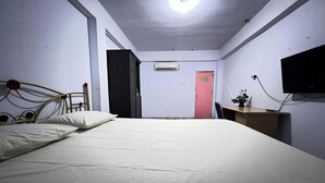 Un dormitorio con cama, escritorio, televisor y aire acondicionado.