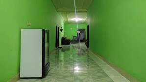 Un pasillo con paredes verdes, un refrigerador blanco y un sofá negro.