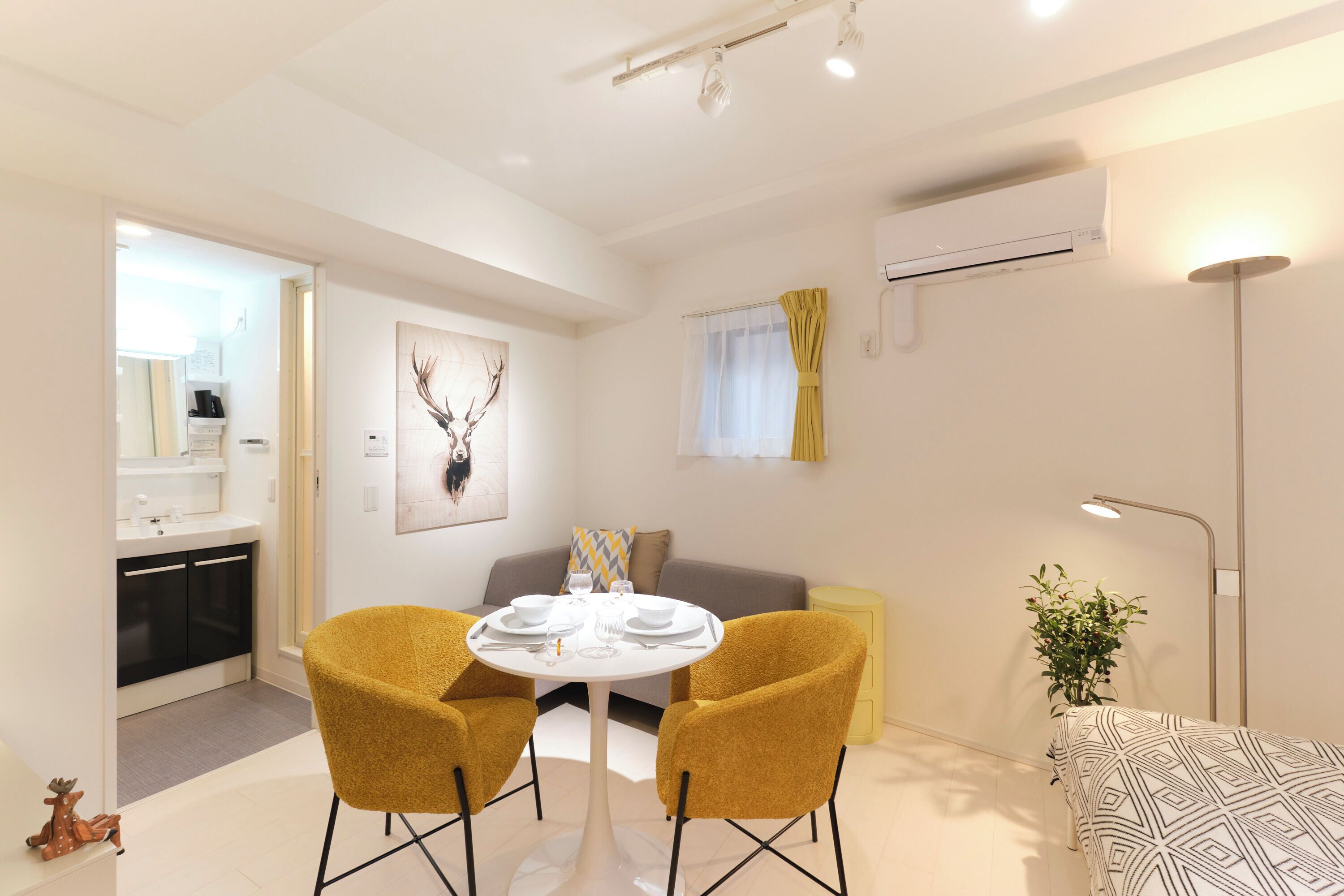 A modern living room with a round table, two yellow chairs, a sofa, and a lamp.