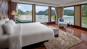 Un dormitorio amplio con una cama grande, vistas a un lago y un barco visible a través de la ventana.