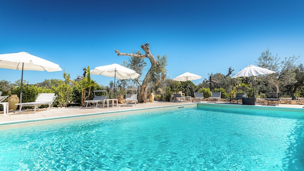 Une piscine d’un bleu éclatant, agrémentée de parasols blancs et de chaises longues.