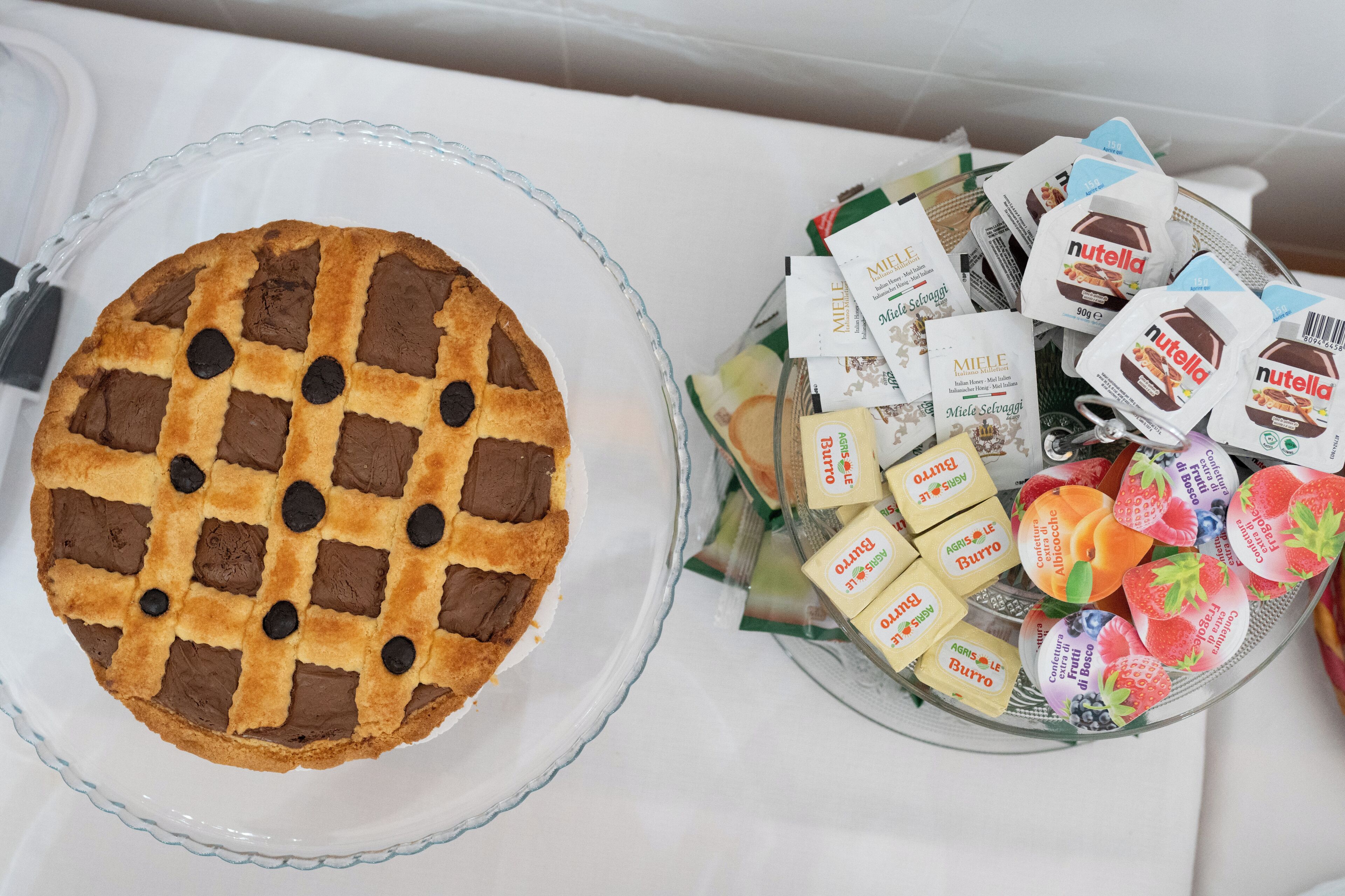Un trozo de tarta sobre un plato de vidrio y un cuenco con alimentos envasados.