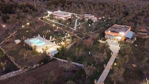 Vue aérienne d’un complexe hôtelier doté d’une piscine, de plusieurs bâtiments et d’un chemin bien éclairé.