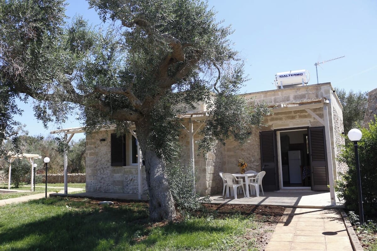 A stone building with a pergola and a table and chairs outside.