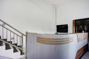 A reception desk with a modern design, a staircase with metal railings, and a flat-screen TV mounted on the wall. - Super OYO Resident- K Syariah (Medan)