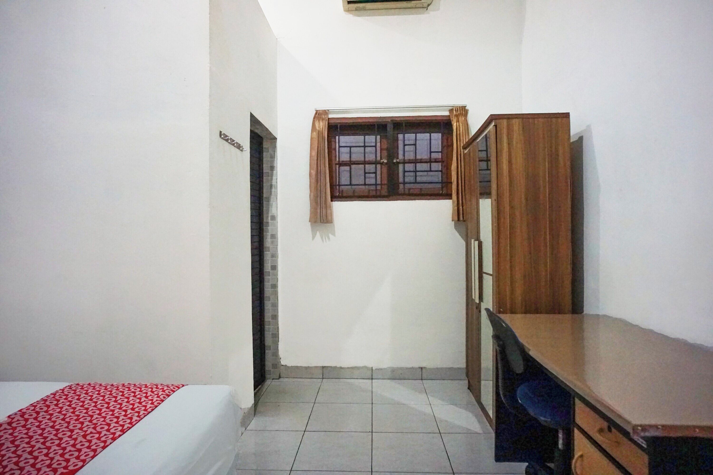 A small, clean room with a bed, a desk, and a window.