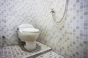 A small bathroom with a toilet, a shower, and tiled walls. - Super OYO Resident- K Syariah (Medan)