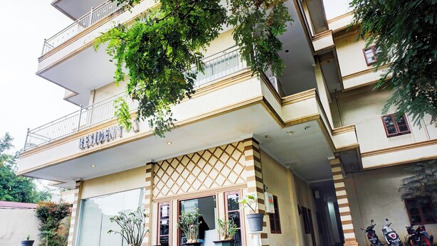 A multi-story hotel with a balcony, potted plants, and parked motorcycles. - Super OYO Resident- K Syariah (Medan)