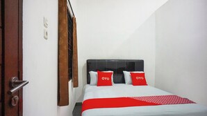 A hotel room with a bed, a red and white bedspread, and a wooden door. - Super OYO Resident- K Syariah (Medan)